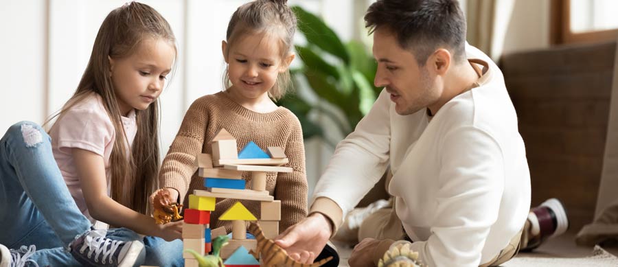 Parent talking with two young daughters while building blocks — illustrating how to educate children about addiction through play and positive communication.