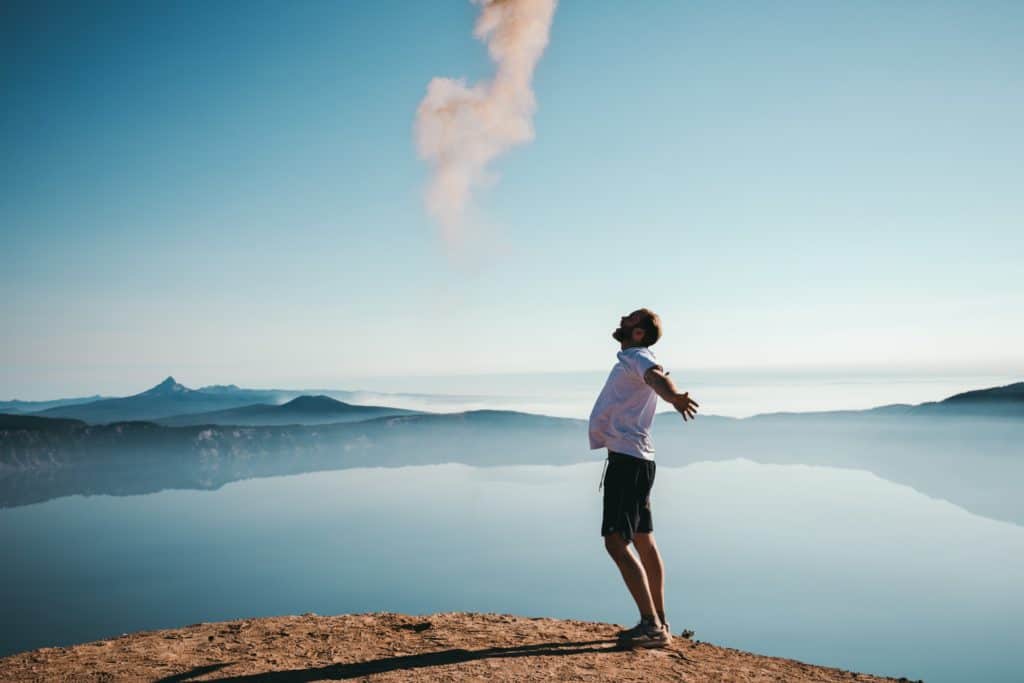A person standing at a scenic cliff, arms open wide to the sky, symbolizing freedom, relief, and renewal that follow a safe and medically supervised detox journey.