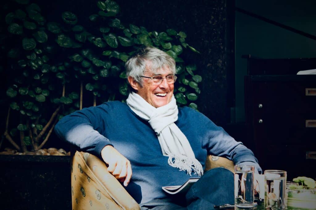 smiling senior man in a blue sweater and white scarf, symbolizing recovery, comfort, and success after alcohol rehab in Austin, Texas.