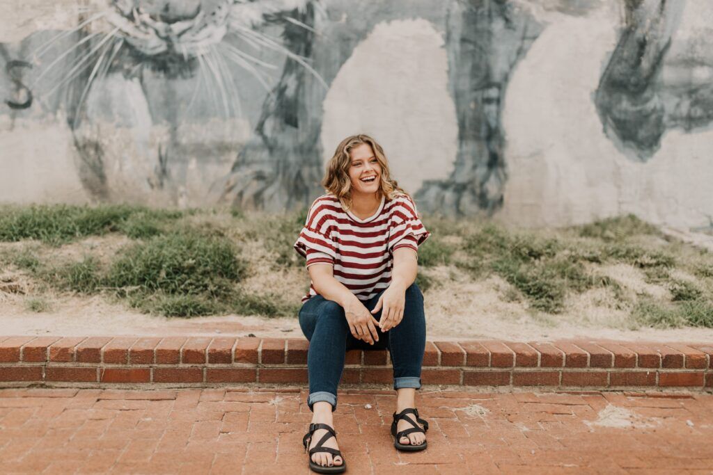Smiling person sitting on brick steps, representing hope and recovery through drug rehab in Austin, Texas.