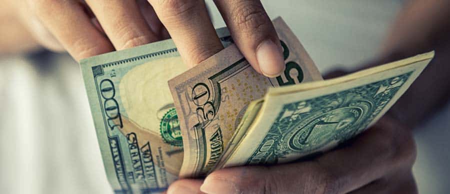 Person counting U.S. cash, illustrating the high cost of illegal drug use and addiction in America.