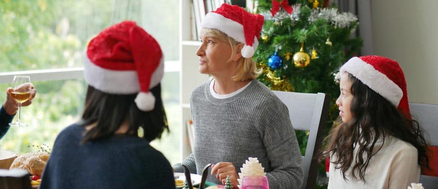 Family celebrating Christmas together with Santa hats, sharing a meal near the holiday tree, symbolizing connection and support during recovery.
