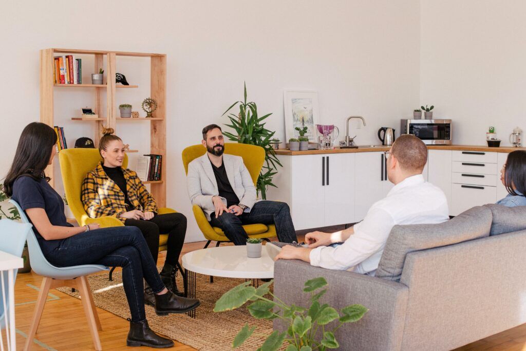 Group therapy session in a cozy Austin counseling room during drug rehab, showing individuals in recovery support engaged in treatment conversation.