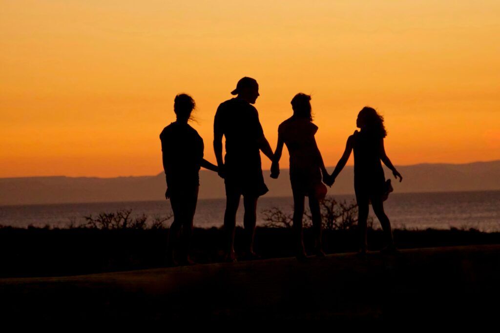Family holding hands at sunset near the ocean, symbolizing unity and recovery in Austin, Texas.