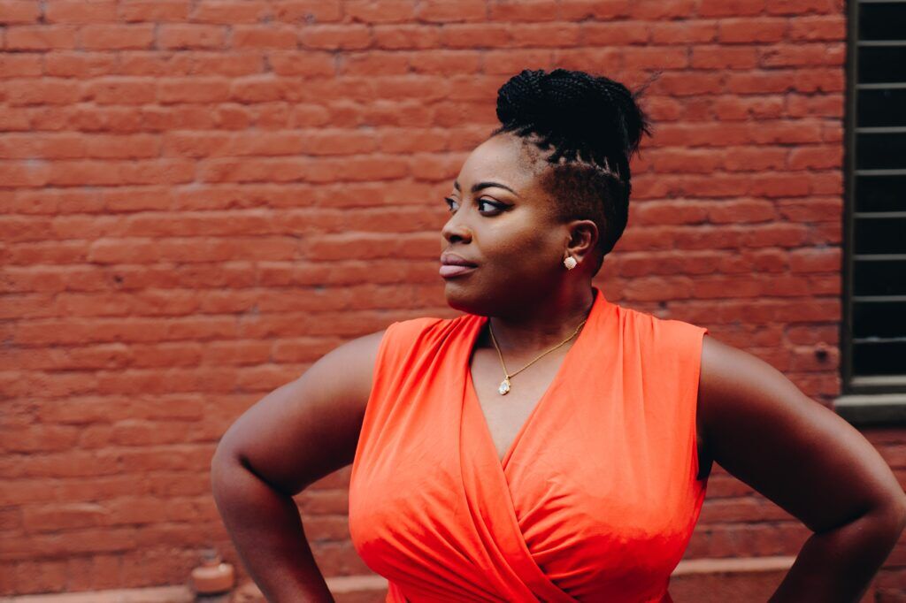 Confident woman standing in front of a brick wall, symbolizing strength and recovery at a drug rehab center in Austin, Texas.