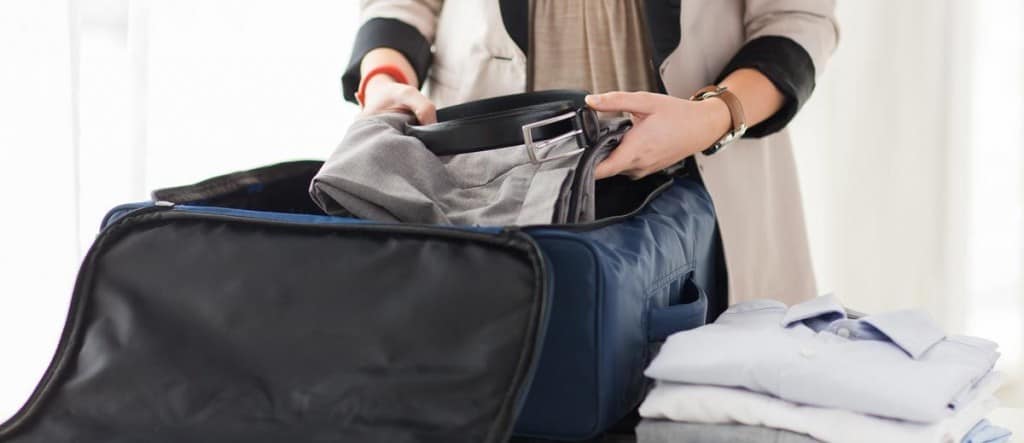 Person packing clothes into a suitcase, representing life transitions and what to expect after rehab.