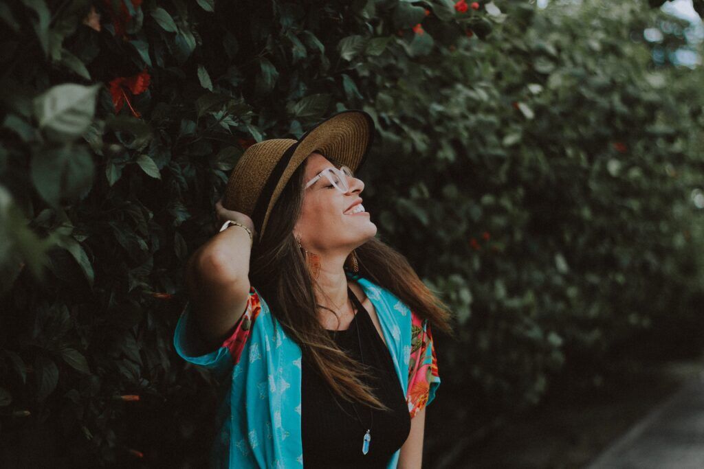 Smiling woman in a straw hat and colorful shirt enjoying a peaceful walk, symbolizing hope and recovery in Austin, Texas.