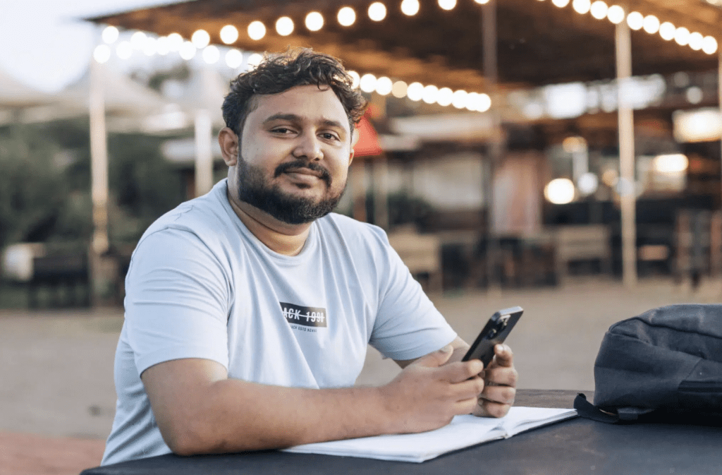 A man seated outdoors with a notebook and smartphone, representing an individual considering rehab options and evaluating treatment plans.