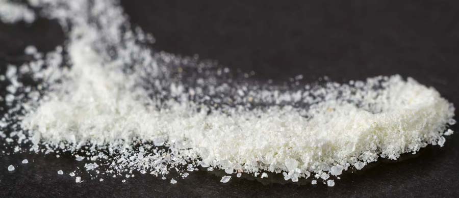 Close‑up of coarse white crystalline powder resembling bathing crystals—commonly used to disguise the appearance of synthetic cathinone ‘bath salts.’